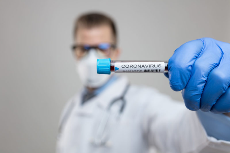 Doctor wearing respiratory mask and holding the Coronavirus blood sample Envatoelements