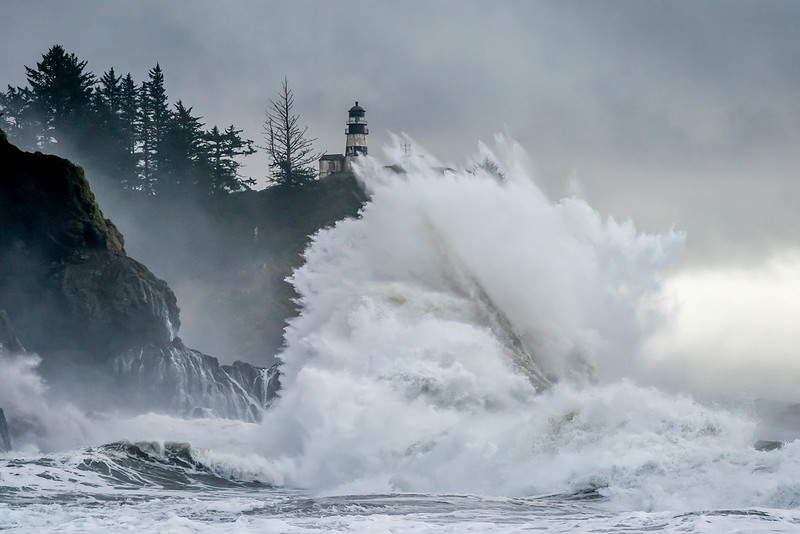 A huge King Tide wave breaking below an Oregon Coast lighthouse