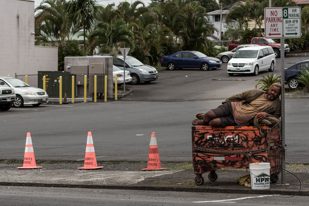 Homeless man sleeping on dumpster in Portland Oregon Homeless man sleeping on top of dumpster near sign in Portland Oregon