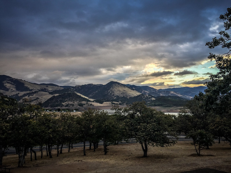 You can just see Emigrant lake through the trees off in the distance. Brown hills rise above it in the background.