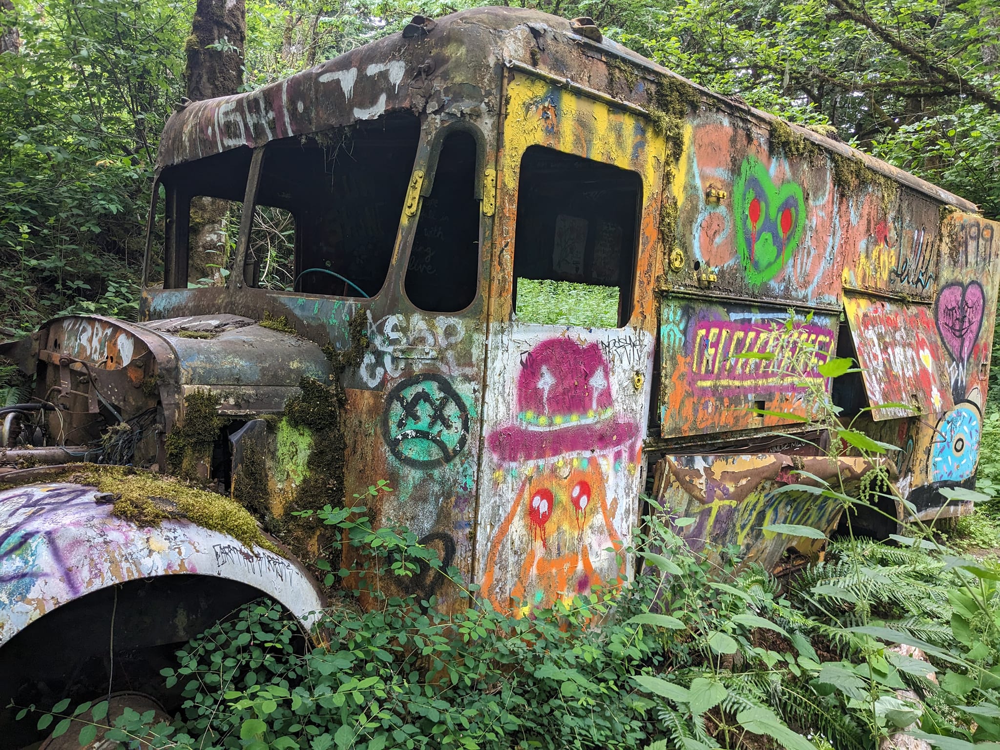Gresham Butte Hike Photo by Photo by Bruce Haney. An old colorful rusted out truck surrounded by greenery and trees.