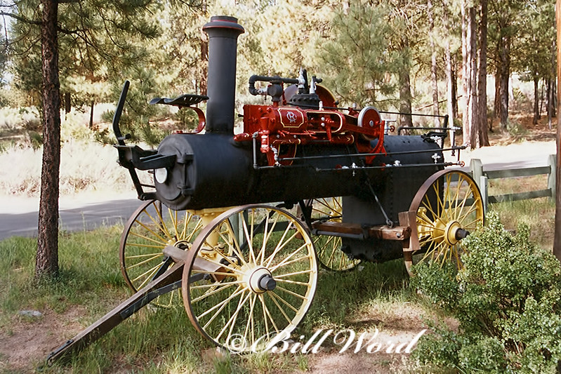 An old piece of logging equipment at Collier Logging Museum. It's black and red and is on old wood spoke wheels.