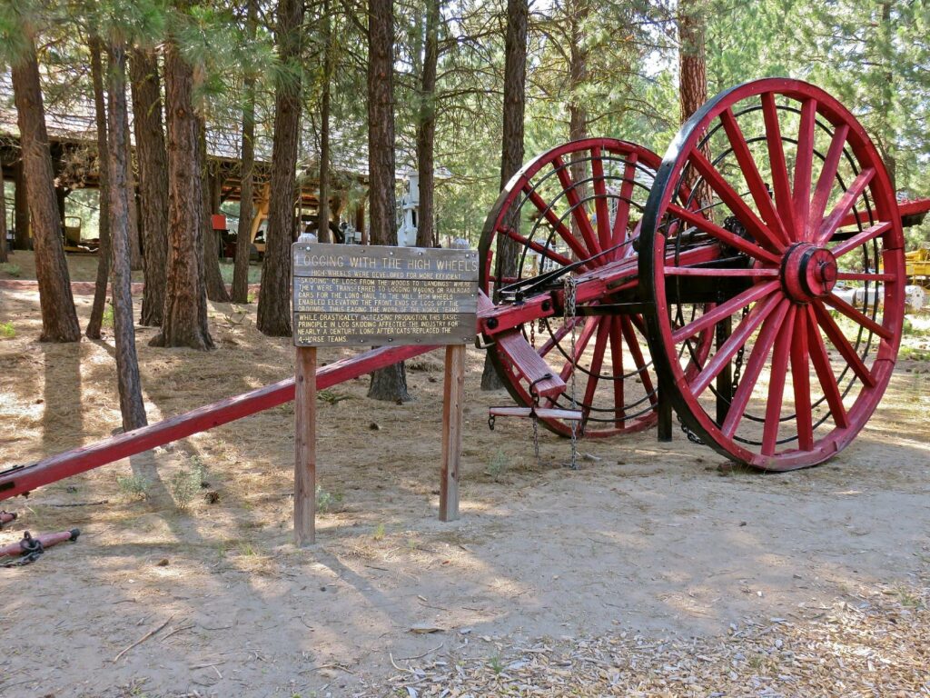 Historic logging equipment at Collier Logging Museum. It's huge and has two large red wood wheels.