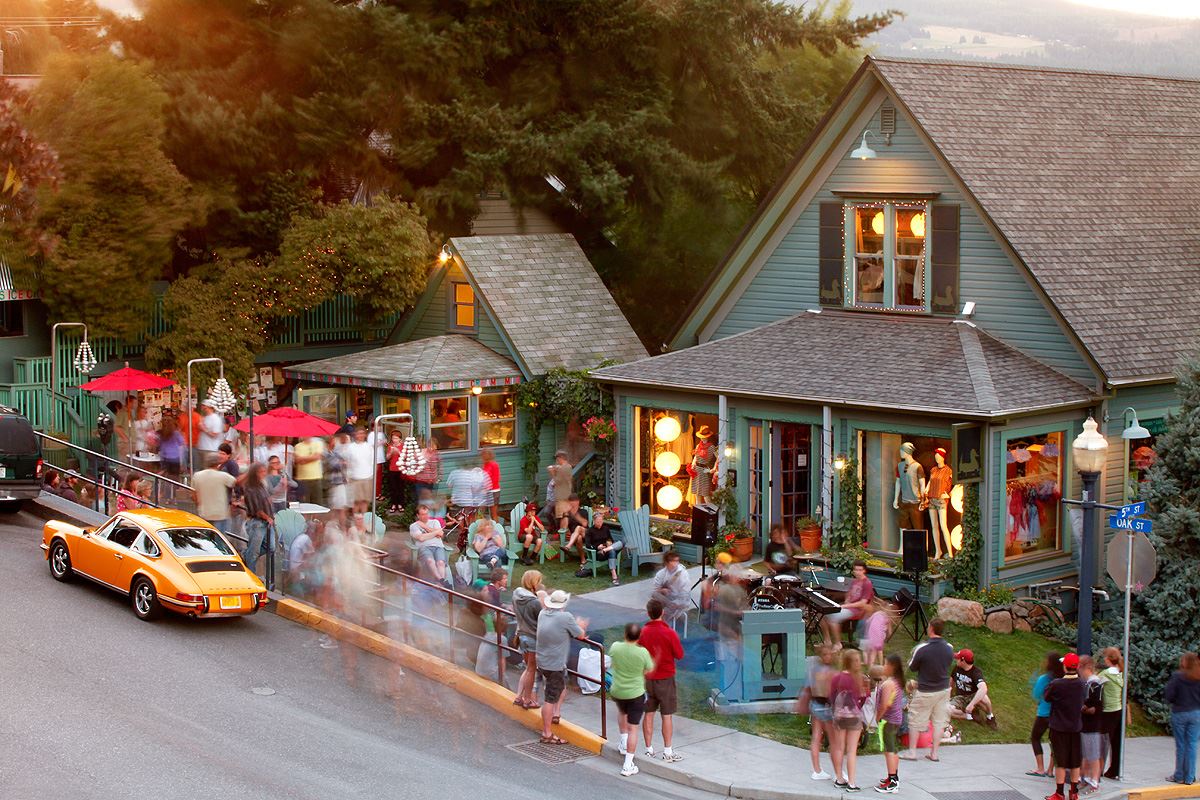 Photo via the Mike’s Ice Cream Facebook page. A zoomed out view of Mike's Ice Cream and the business next door. Both look like green houses, and there is a crowd of people outside on the lawn and lounging in chairs eating ice cream.