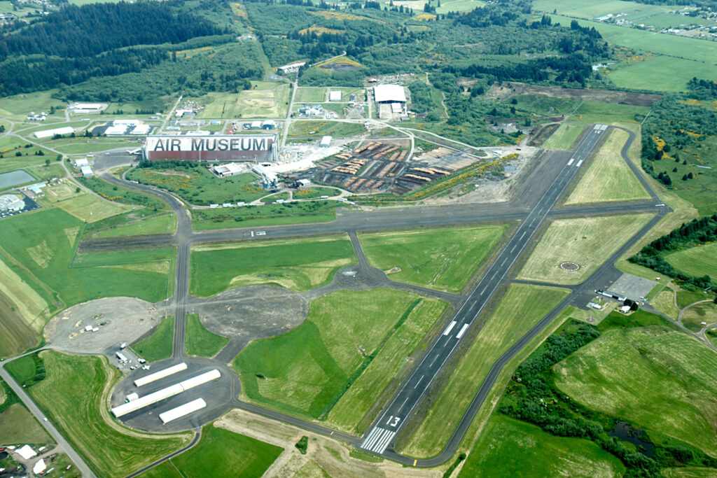 A colored aerial photo of the Tillamook Air Museum and the surrounding runways and green fields. In the photo, a lumber yard is next door to the air hangar. tillamook air museum, planes, WWII, history, family things to do, oregon coast