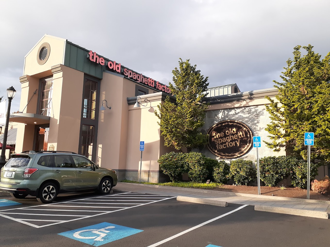 Photo by Rodrigo Castro via Google Local The outside of The Old Spaghetti Factory in Hillsboro, Oregon. It's a tall white building with a green metal roof. there are shrubs and small trees outside.