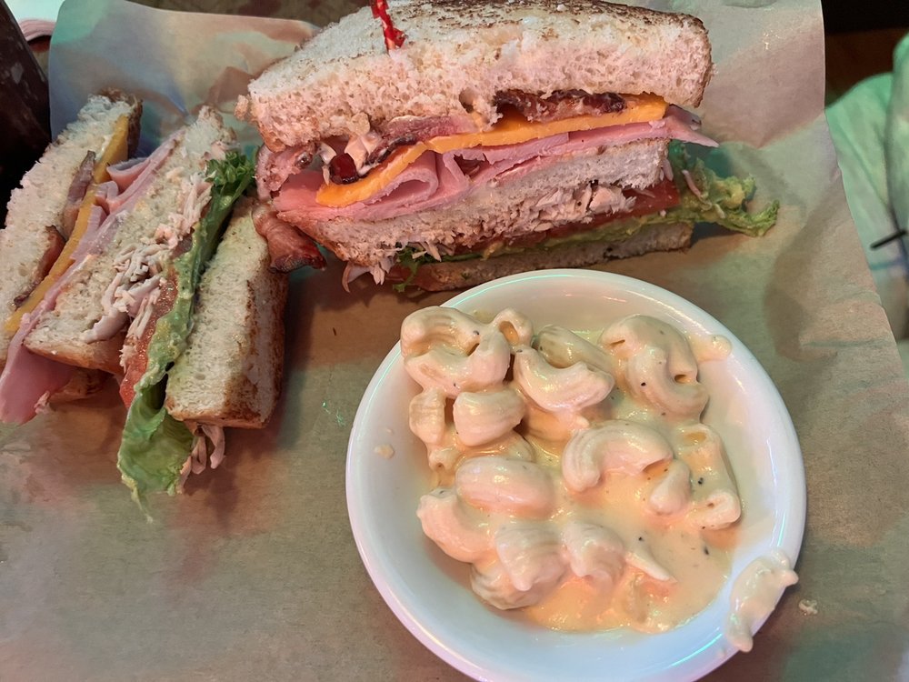 A meat sandwich with a bowl of mac and cheese.