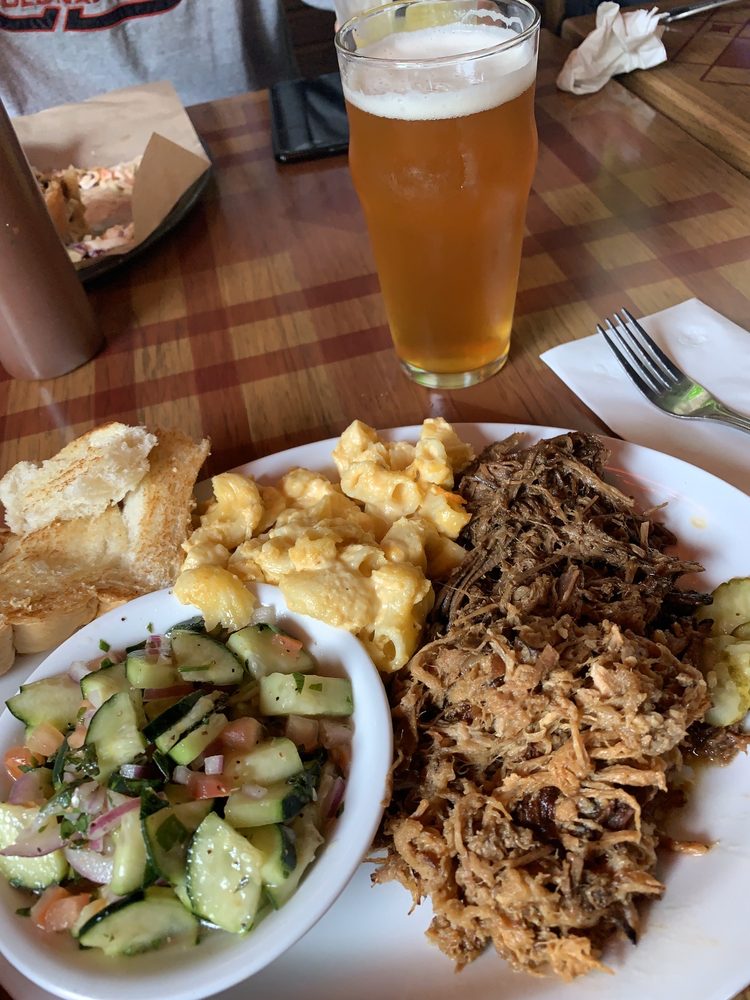 A delicious looking plate of food with shredded meat, cucumber salad and macaroni.