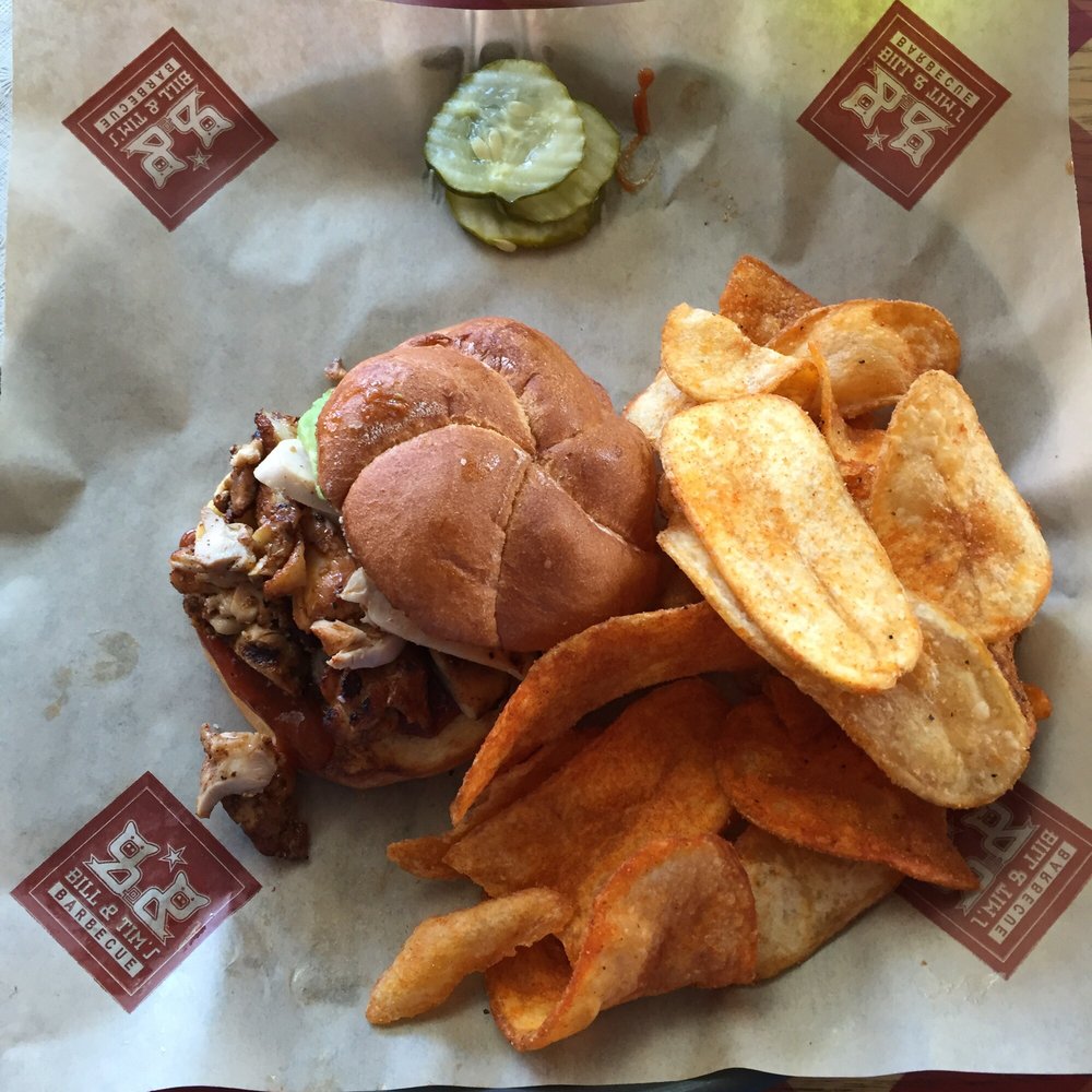 A burger with barbecue chips and pickle slices.