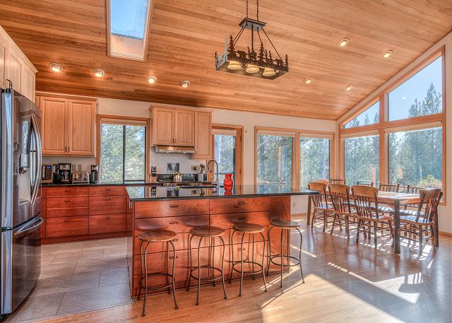 The kitchen and dining area of Belknap #4. There's vaulted wood ceilings, arm wood tones and lots of natural lighting.