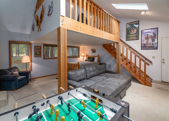 The interior of Duckpond #2. There's a bed, a gray couch and foosball table as well as stairs leading up to another floor.