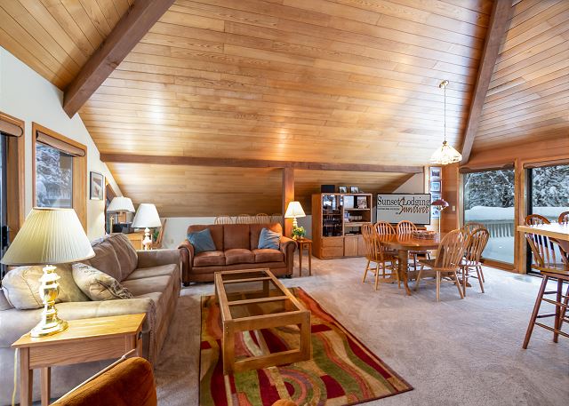 The interior of Hickory #20. There are brown couches inside, a large vaulted ceiling with light wood tones, and soft looking gray carpet. The room is well lit by natural light.