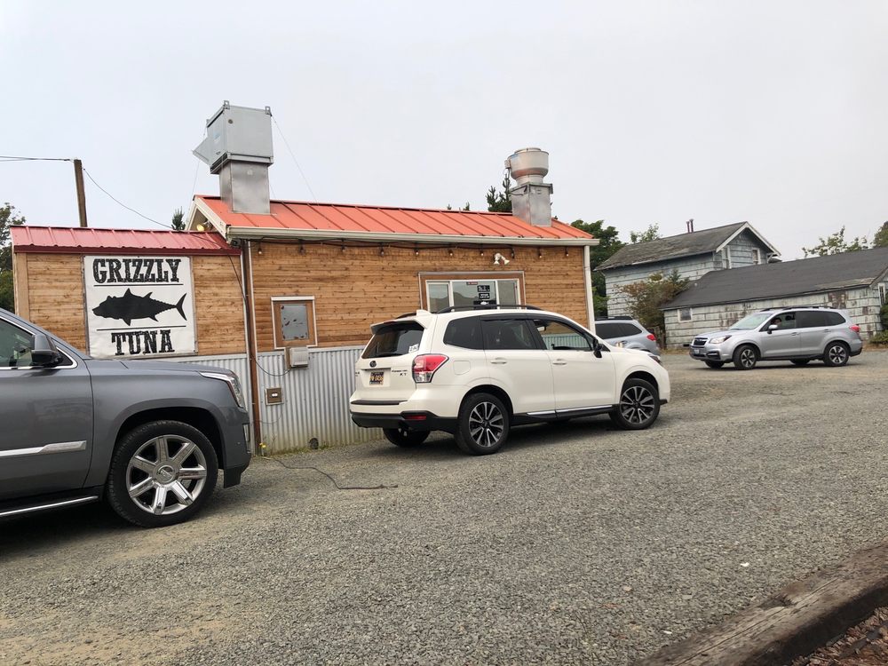 A white SUV, and a dark silver SUV in the drive thru line at Grizzly Tuna.