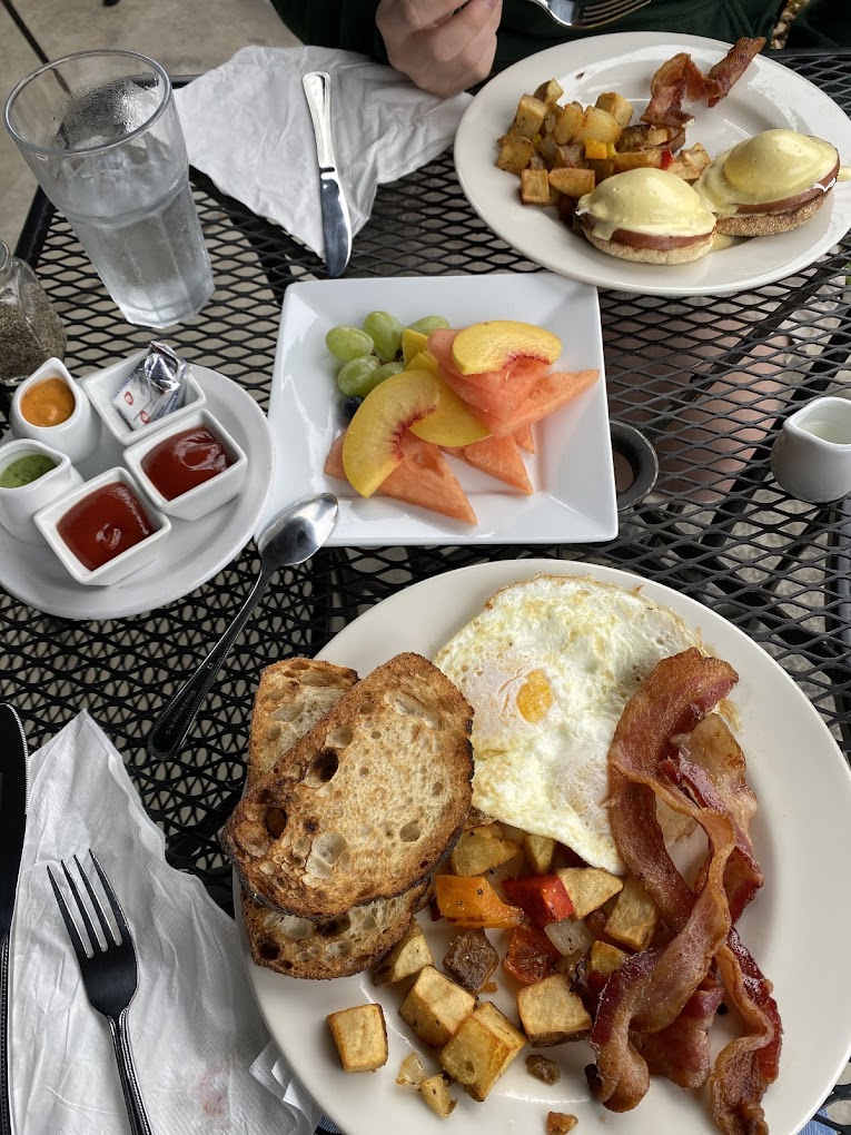 Several plates of delicious looking food on a black metal outdoor table.