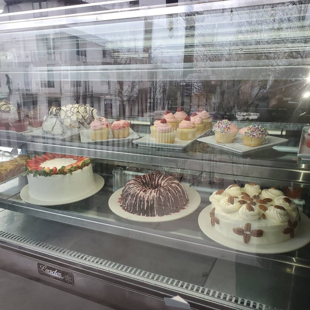 A glass display case with lots of gorgeous cakes inside.