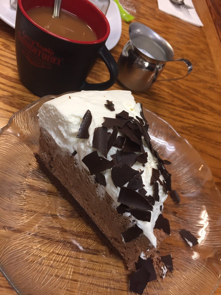 A slice of a chocolate cake with a white topping and shaved chocolate ont op.