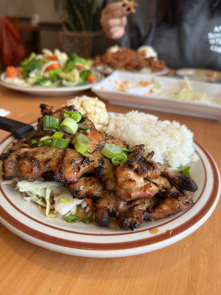 A plate with mac salad, sticky rice and marinated meat with chopped green onion on top.