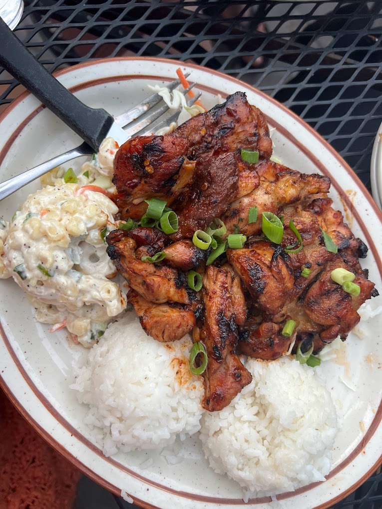A plate with mac salad, sticky rice and marinated meat with chopped green onion on top.