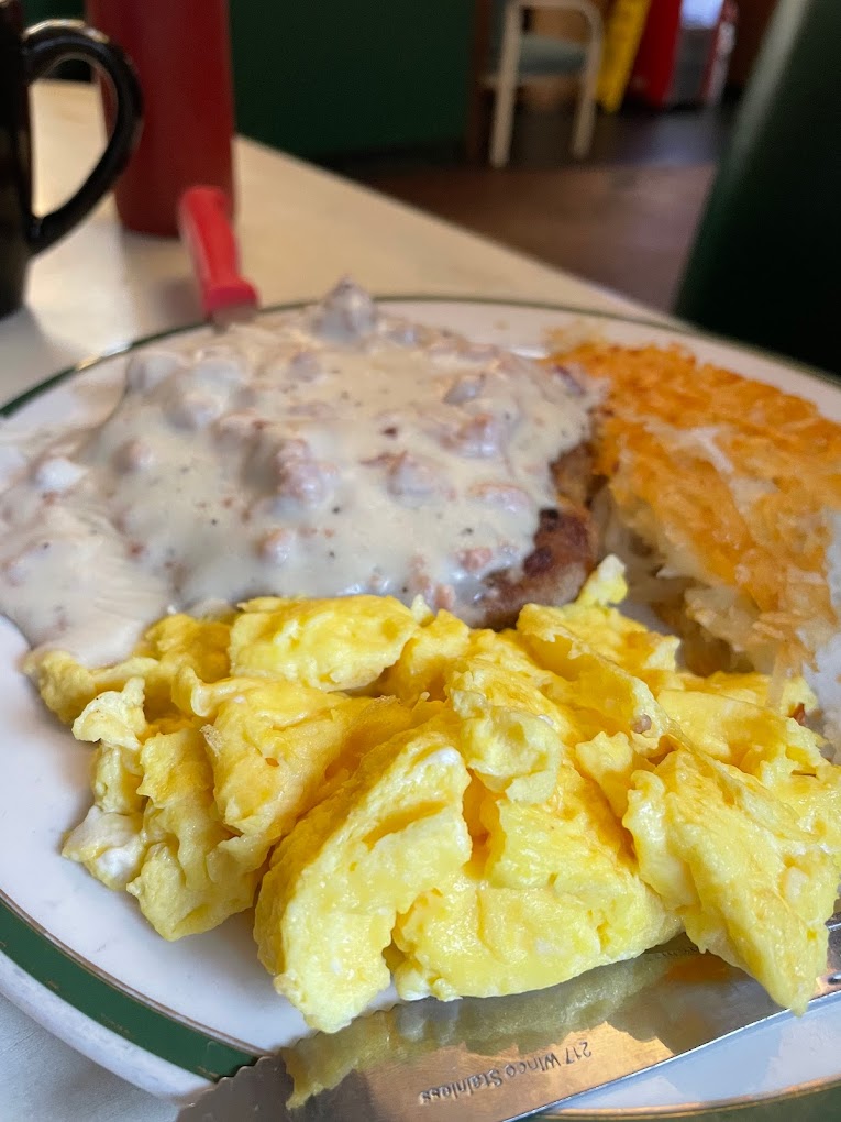 Eggs, hash browns and other delicious breakfast food on a white plate.