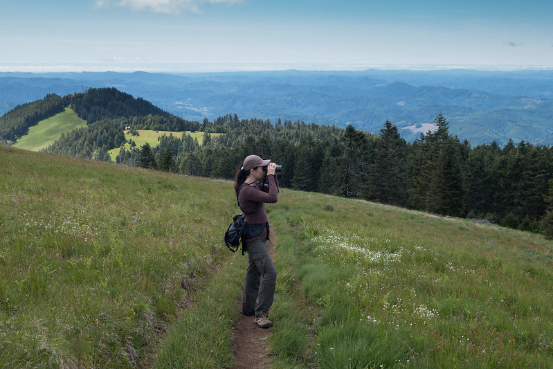 A woman looks through binoculars on Marys Peak