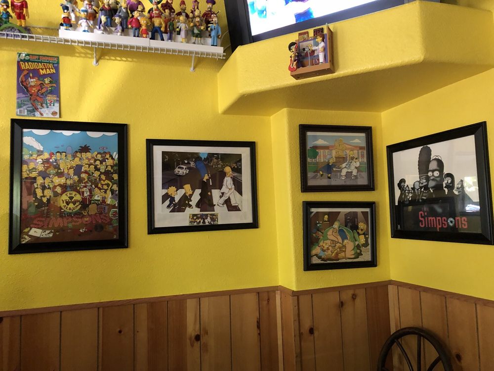 Simpson's art pieces on a bright yellow wall.