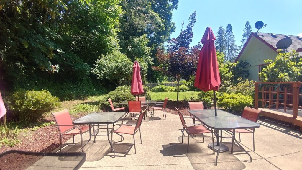 The outdoor patio at Ike's Pizza. There are tables with red chairs and red umbrellas.