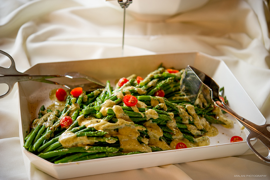 Asparagus and cherry tomatoes plated nicely on a white plate and drizzled in a creamy sauce.