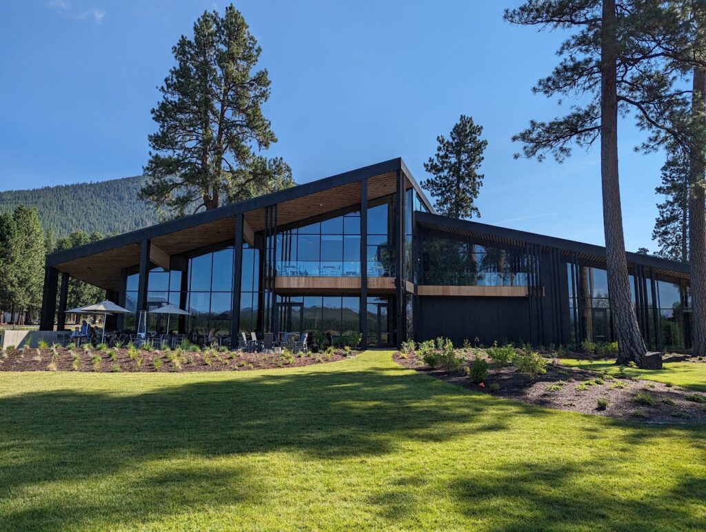 The outside of The Lodge Restaurant. It features wood tones, large windows, the color black, and modern Pacific Northwest style architecture.