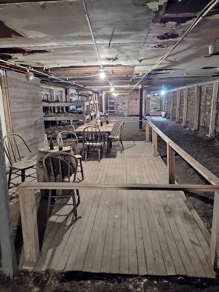 An old room with wooden floors, rails and walls with wooden chairs under ground.