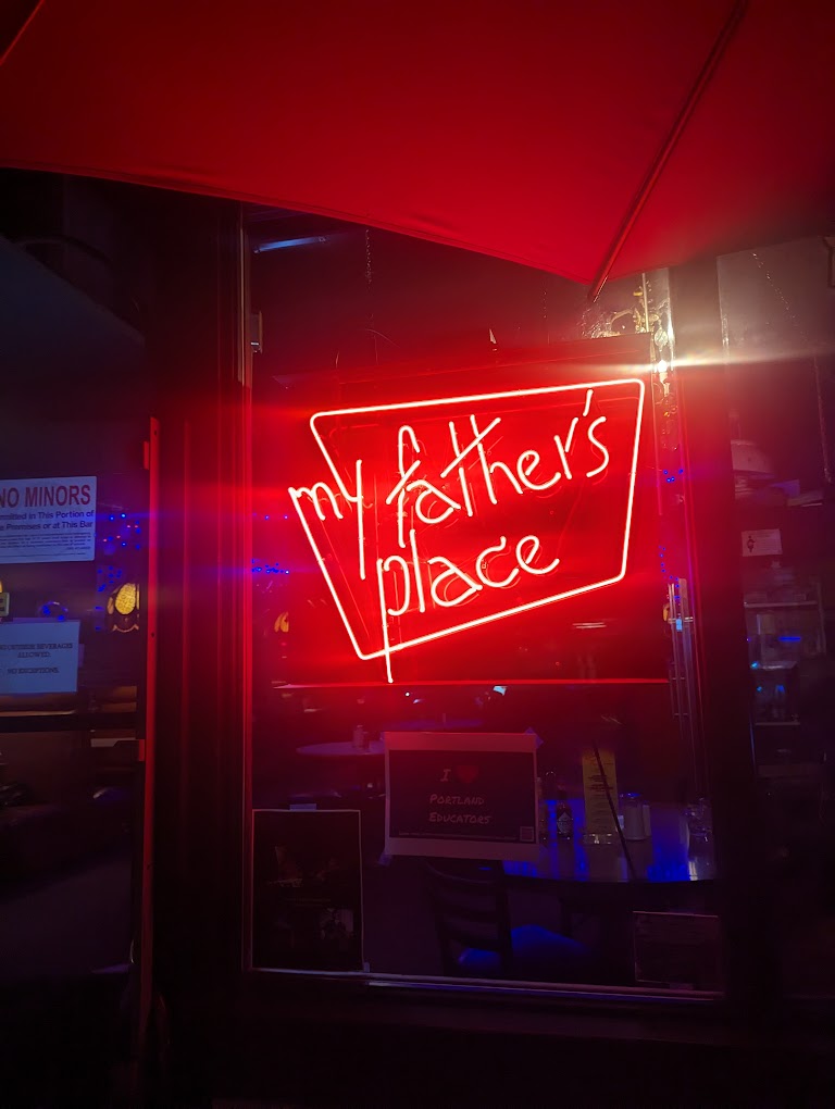 The red neon My Father's Place sign in the window at night.
