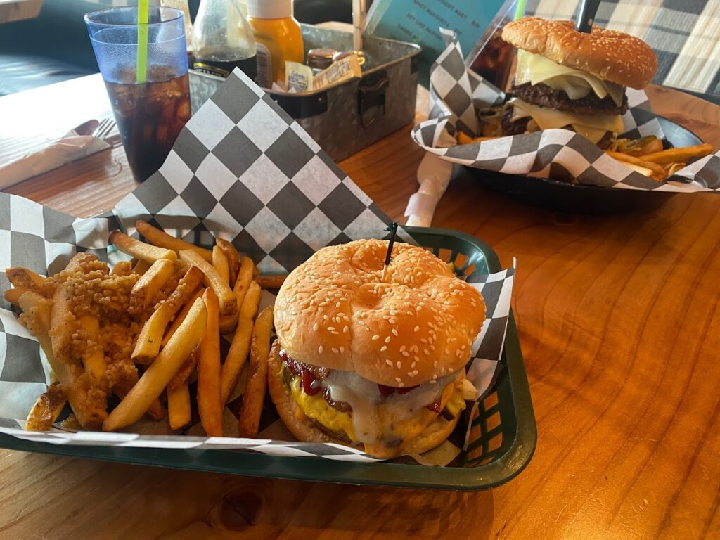 A tasty looking burger and fries in a plastic basket with a black and white checkered paper wrapper.