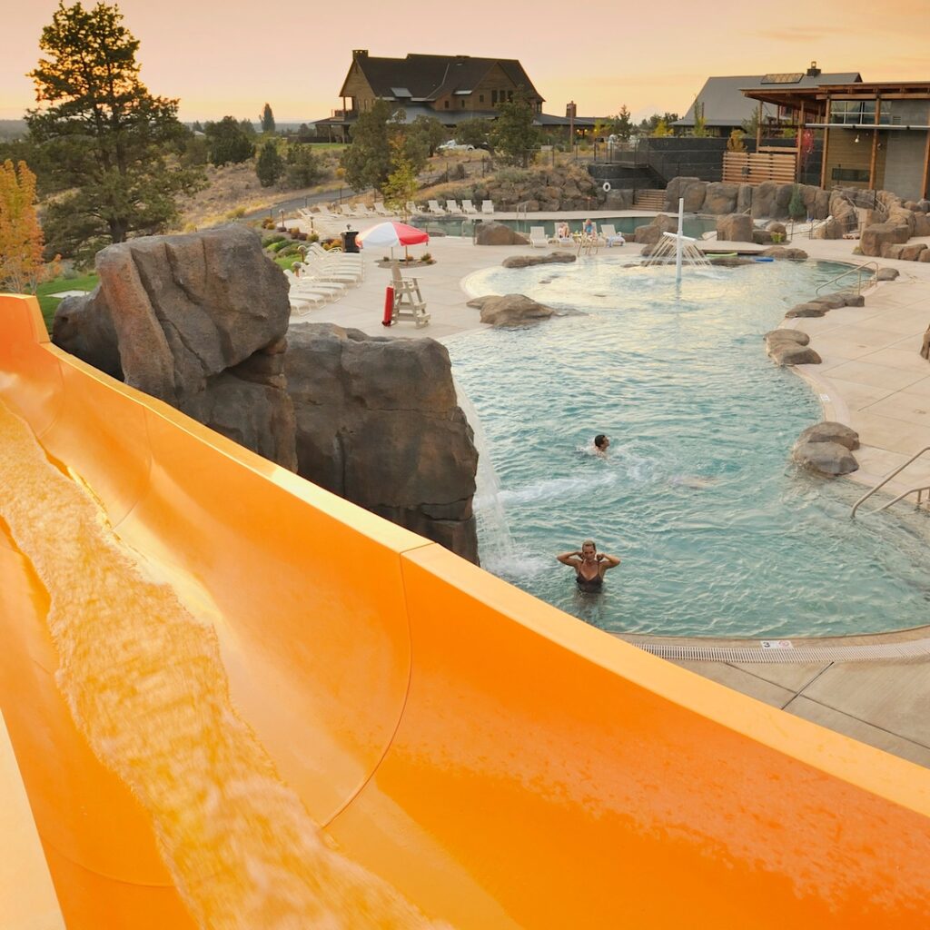 A bright yellow slide above an outdoor swimming pool at Brasada Ranch.