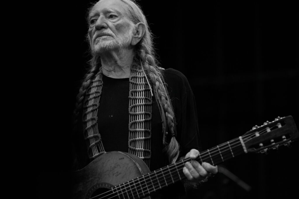 A black and white photo of Willie Nelson holding a guitar. Summer concerts, Oregon, Things to do, 2024
