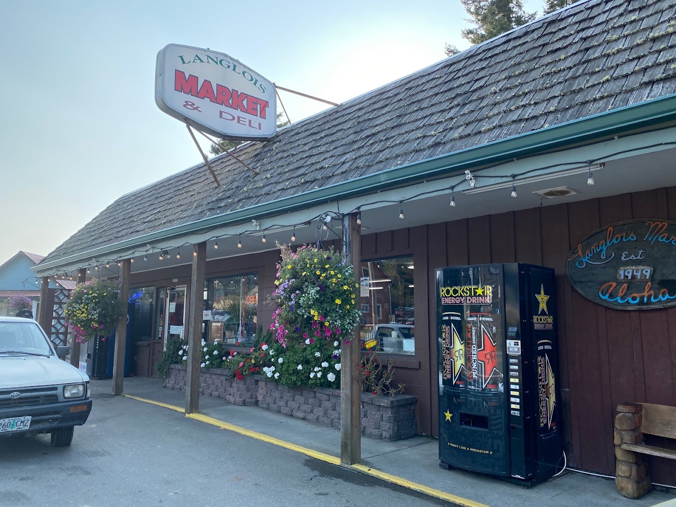 Photo by Oregon Coast VIP Marketing via Google Local. The outside of the Langlois Market. It's a brown building with a brown shingle roof, and green trim.