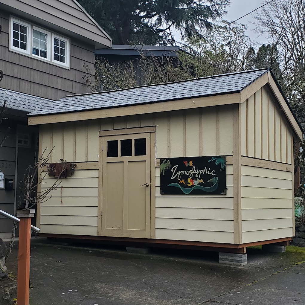 The Zymoglyphic Museum. Photo by Jamie Jefferson via Google Local. A building in the driveway of the Zymoglyphic Museum with a sign proclaiming the museum's name. The museum is upstairs.