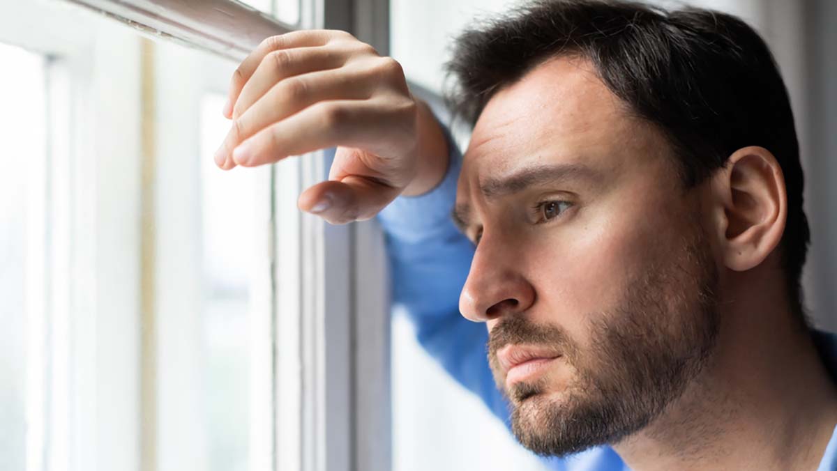 A,Man,Stands,By,A,Window,,Gazing,Out,With,A man deep in thought