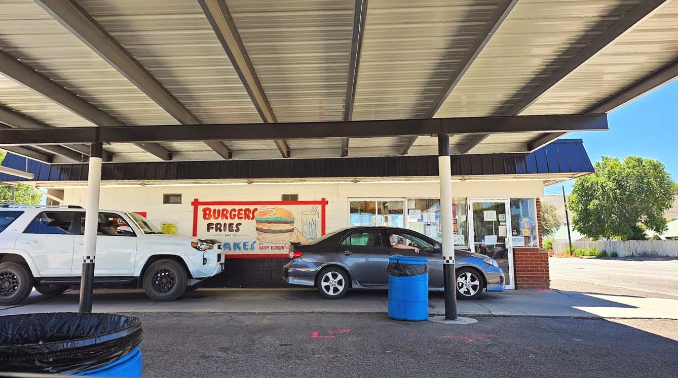 Photo by Stacy S. via Google Local. A black car and a white SUV in the covered drive through at Burger Bob's Drive-In, in Baker City, Oregon.