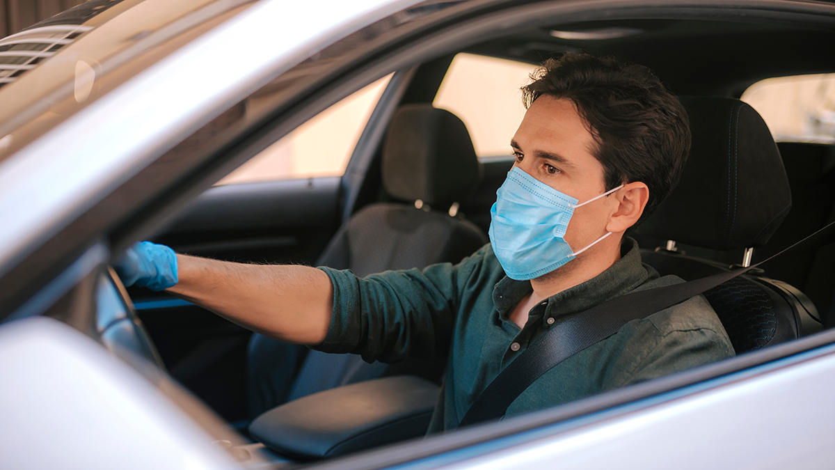 A,Man,Driving,A,Car,Puts,On,A,Medical,Mask
