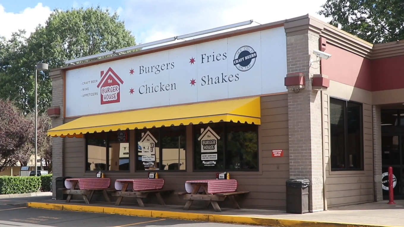Photo by The Burger House via Google Local. The outside of The Burger House. It's a brown brick building with a friendly yellow awning, and a large white sign with black words declaring: 'Burgers, Fries, Chicken, Shakes'.
