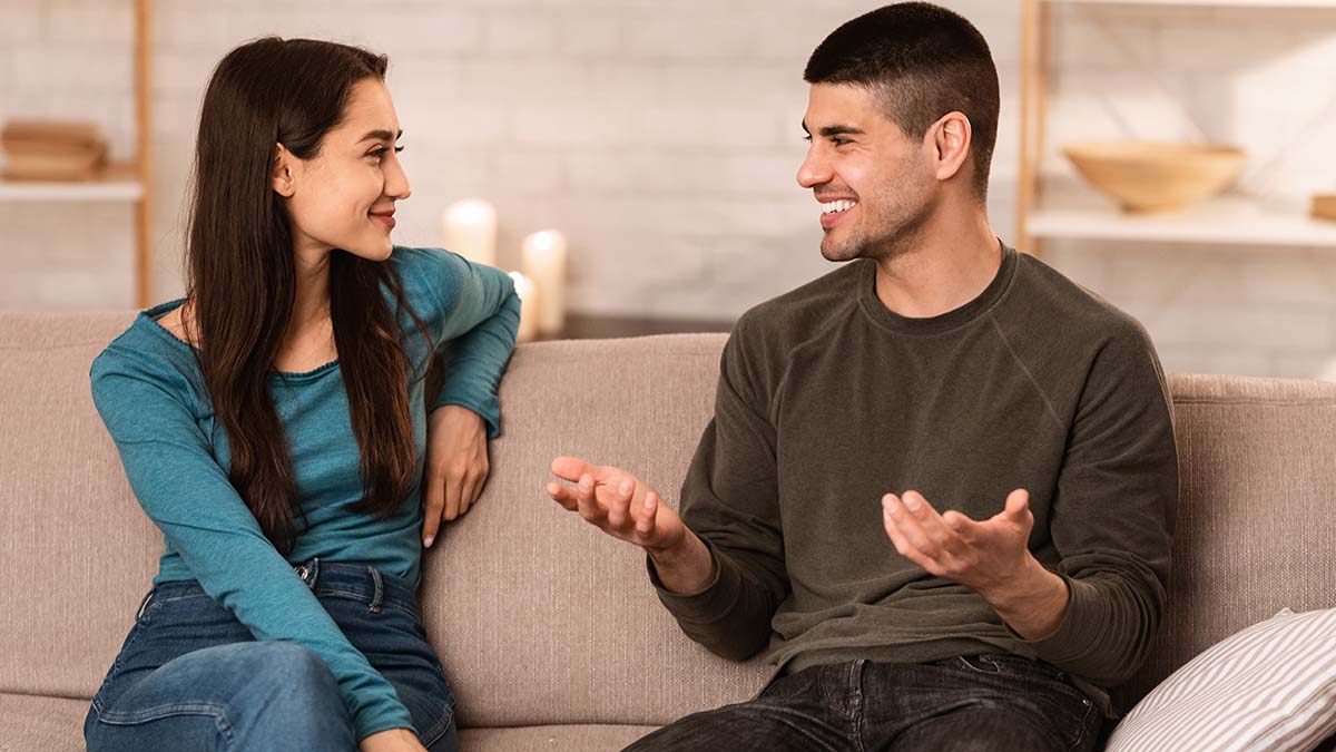 Beautiful,Couple,Talking,,Sitting,On,Couch,At,Home,,Have,A two people chatting