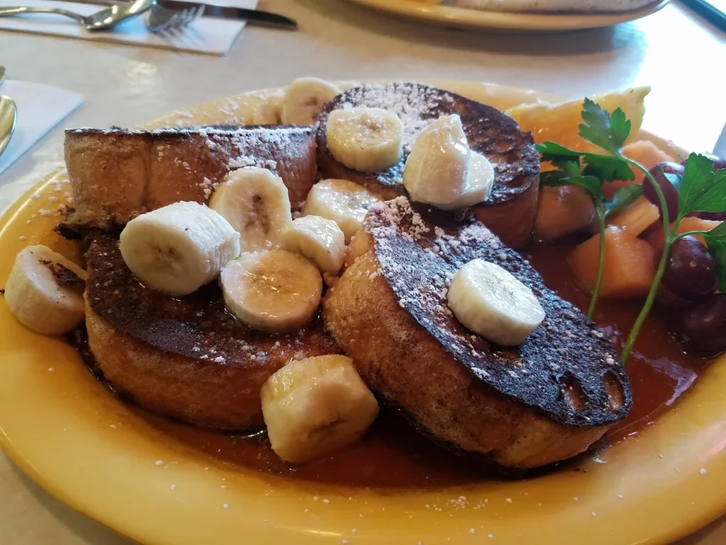 Round French toast with banana slices on top and syrup. I've never seen French Toast that looks like this before. They are super tall and thick looking, almost like a really thick English Muffin in shape and size. It looks delicious!