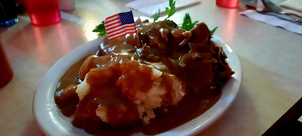 Potatoes, meat and gravy with a little American flag sticking out of the meal on a toothpick.