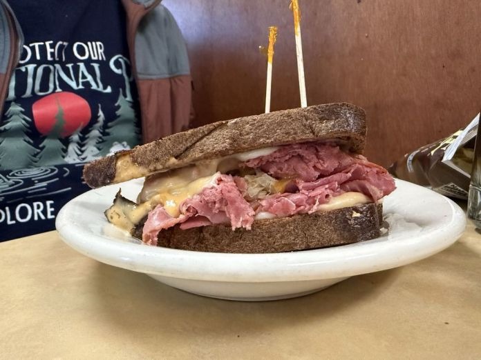 Corned beef Reuben sandwich with melted Swiss cheese and sauerkraut on dark rye bread at a Portland German deli