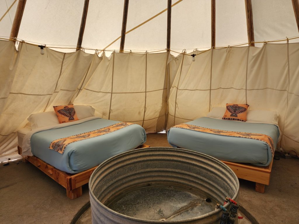 Inside a teepee at Crystal Crane Hot Springs with queen bed and wooden soaking tub